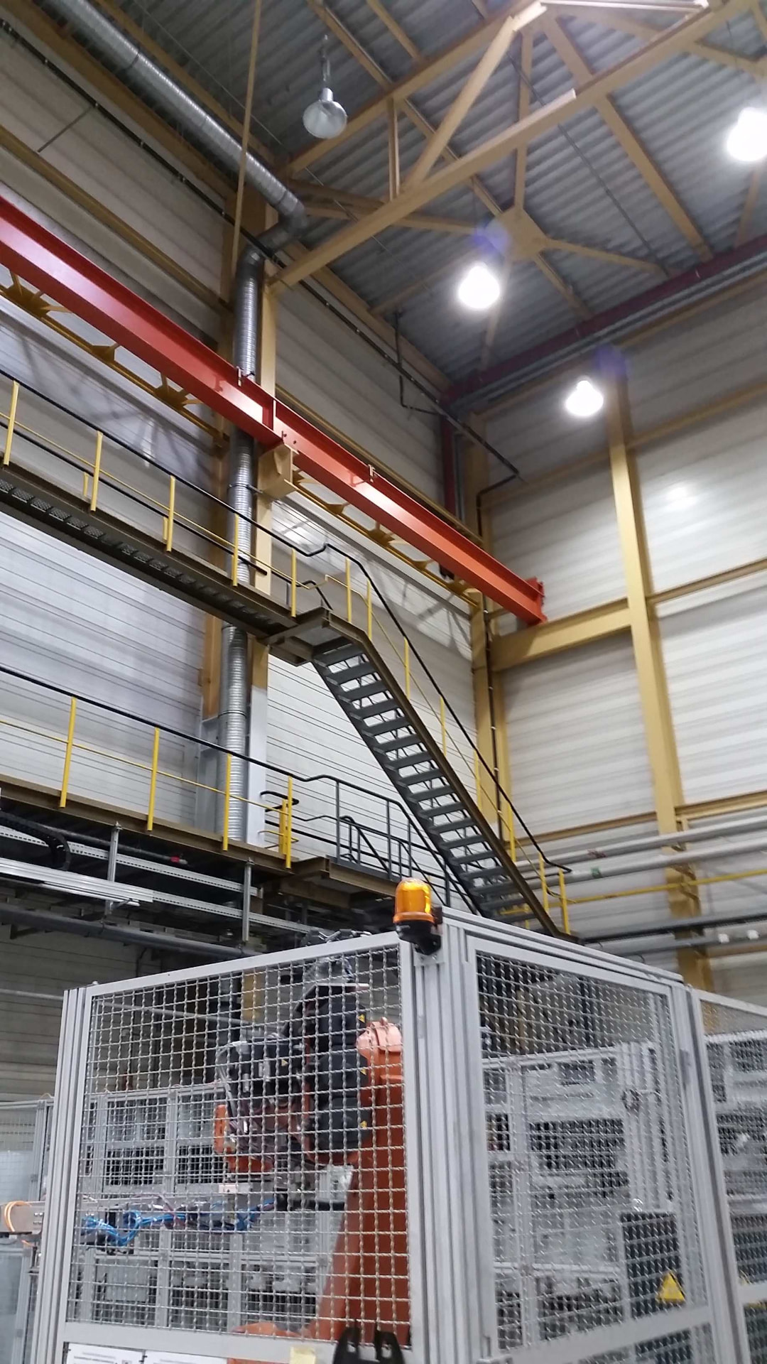 Industriehalle mit rotem Kran, Stahltreppe und Maschinenumhausung