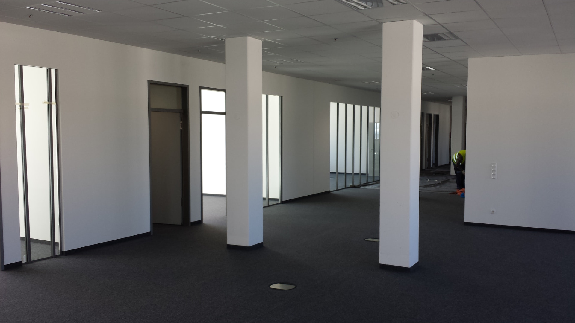 Weiß gestrichenes Büro mit dunklem Teppichboden und weißen Stützen